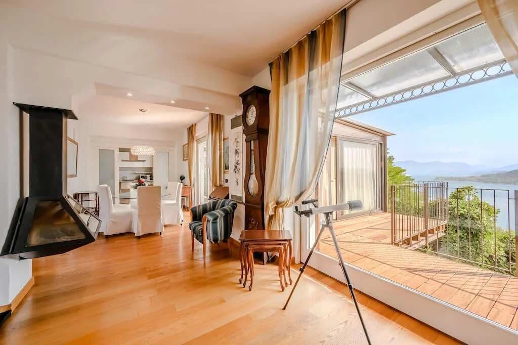 Un salón amplio con suelo de madera, una mesa de comedor y un balcón con vistas al paisaje.