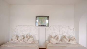 Una habitación con dos camas, cada una con cabecero blanco y almohadas a rayas.