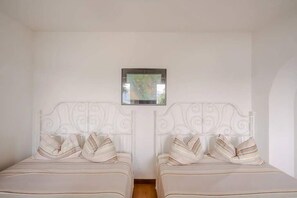 A room with two beds, each with a white headboard and striped pillows. - Villa Arona 4br/2ba Sleeping up to 14 Guests (Arona)