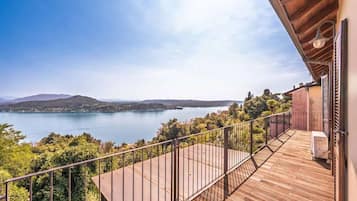 A wooden deck with a metal railing overlooking a lake and hills.
