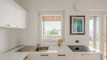 A modern kitchen with white cabinetry, a stainless steel sink, and a window with a view of greenery.