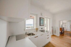 Una cocina moderna con armarios blancos, un lavamanos de acero inoxidable y vistas al exterior.