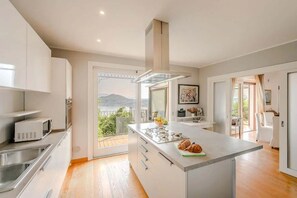 Una cocina moderna con una isla grande, electrodomésticos de acero inoxidable y vistas al exterior.