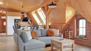 Ein Loft-Wohnbereich mit Holzboden, einem grauen Ecksofa, einem Couchtisch aus Holz und einer Ziegelwand.