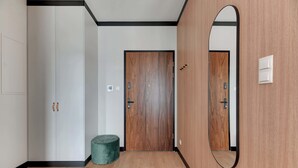 Un corridoio con una porta in legno, uno specchio e un poggiapiedi verde.