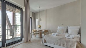 Ein Schlafzimmer mit einem Bett, einem Esstisch, Stühlen, einer Pendelleuchte und Blick durch eine Glastür.