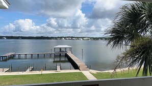 Une vue sur un lac avec une jetée qui s’avance dans l’eau, entouré de verdure et sous un ciel dégagé.