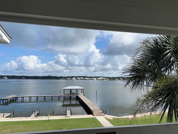A view of a lake with a dock extending into the water, surrounded by greenery and a clear sky. - Lagoon Front Paradise with Beach Access (Gulf Shores)