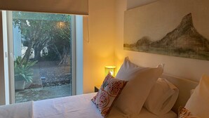 A bedroom with a bed, a window with a view of trees, a lamp, and a painting on the wall. - Welcome to C'an Felip in Artà (Artà)