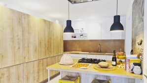 A modern kitchen with wooden cabinets, a central island with stools, pendant lighting, and a gas stove. - Welcome to C'an Felip in Artà (Artà)