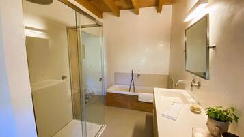 Une salle de bain moderne avec une douche en verre, une baignoire, un lavabo avec un miroir et une plante en pot.