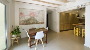 A dining area with a wooden table, white chairs, a potted plant, and a large abstract painting on the wall. - Welcome to C'an Felip in Artà (Artà)