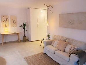 Una sala de estar moderna con un sofá, un escritorio, una lámpara y una planta en maceta.