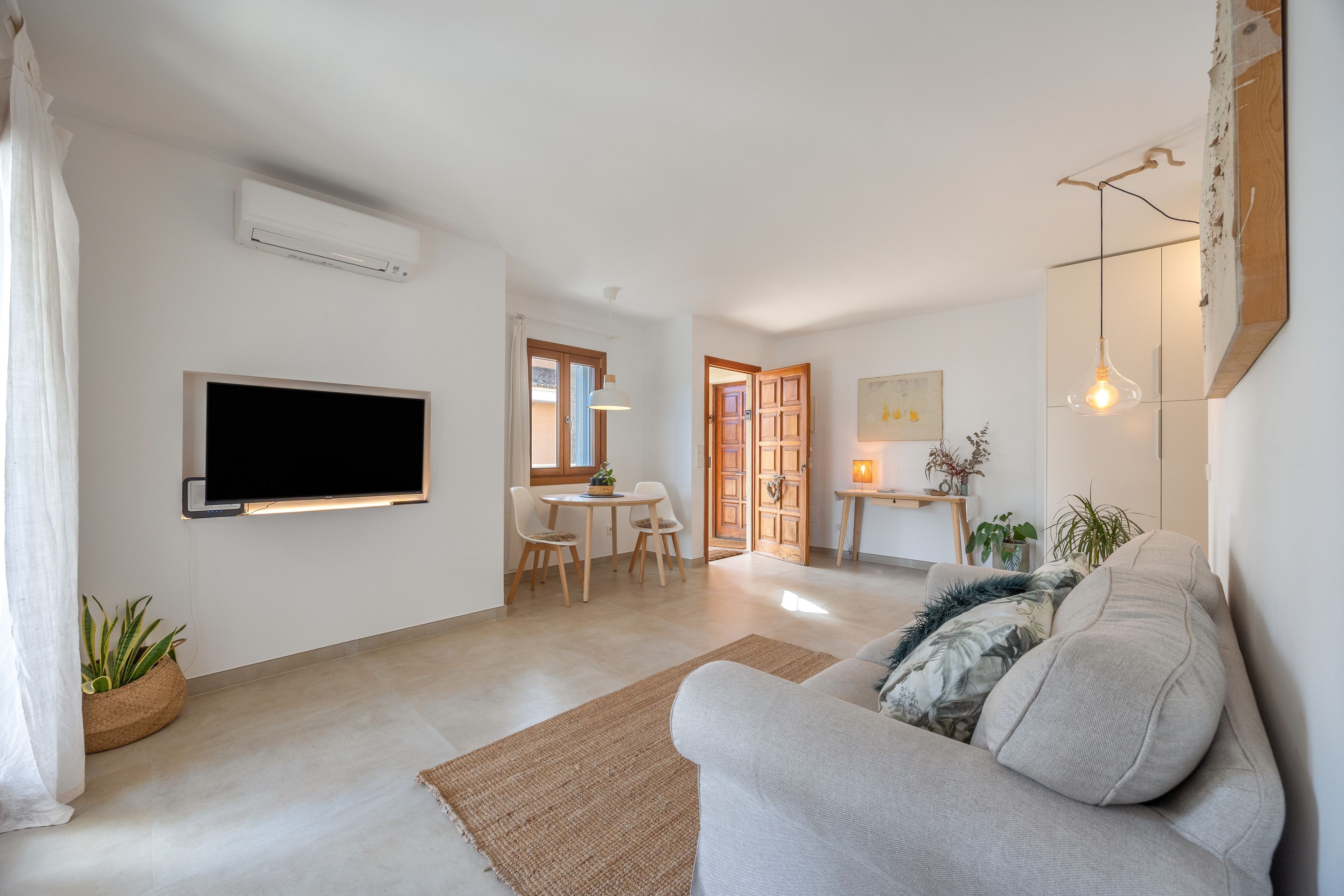 Una sala moderna con una televisión de pantalla plana, un sofá y un comedor con sillas.