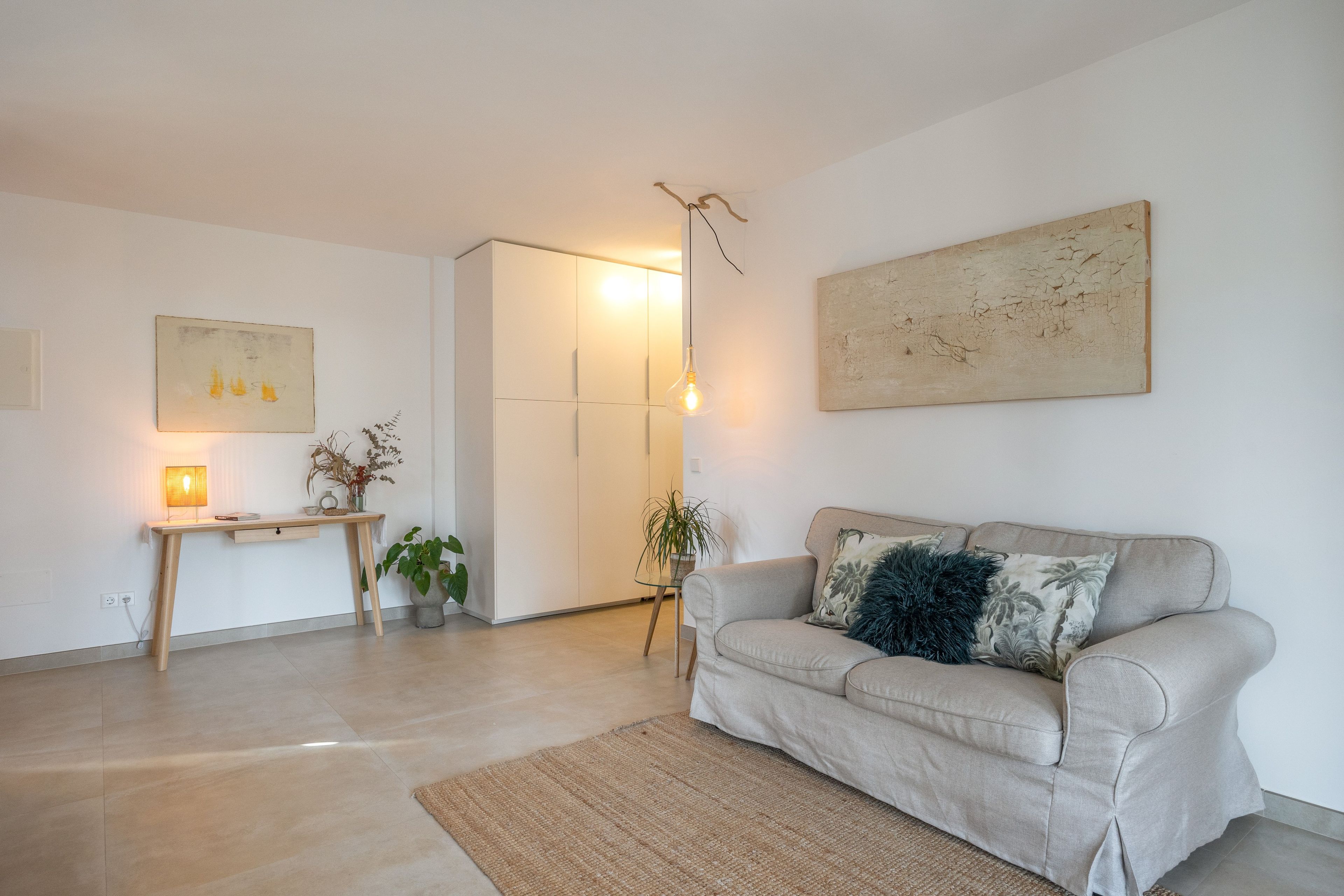 Una sala de estar con un sofá, una mesa y una lámpara.
