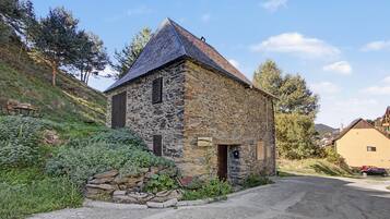 A stone building with a sloped roof, a wooden door, and a sign indicating its name.