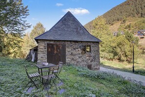 A stone cottage with a pitched roof, a wooden door, and a small window.