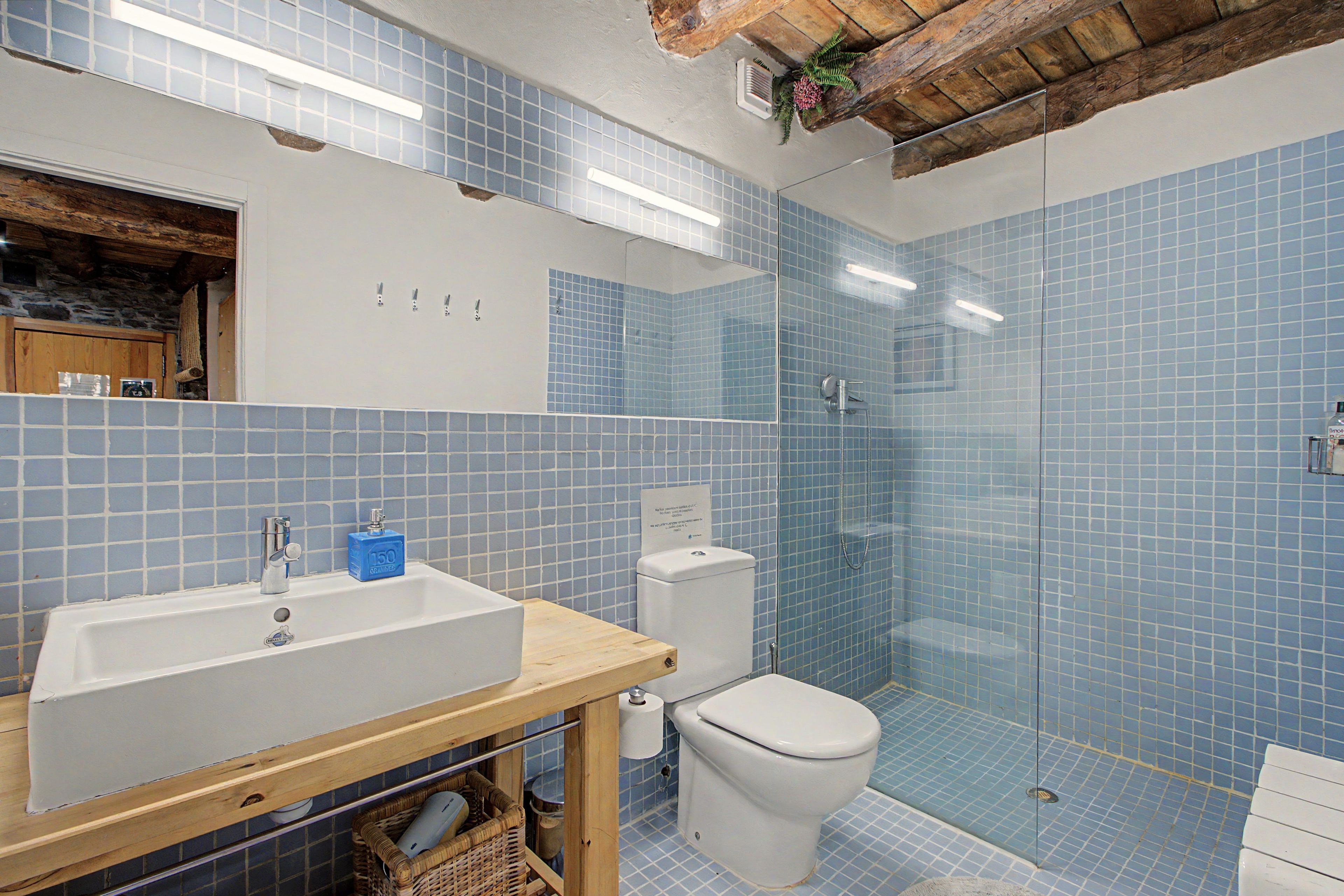 Et badeværelse med en hvid vask, toilet og bruseområde.