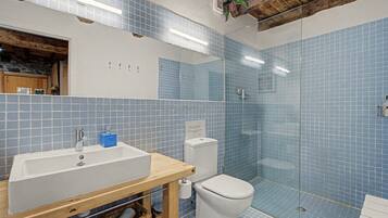 Et badeværelse med en hvid vask, toilet og bruseområde.