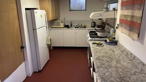 A kitchen with white cabinets, a microwave, a stove, and a window.