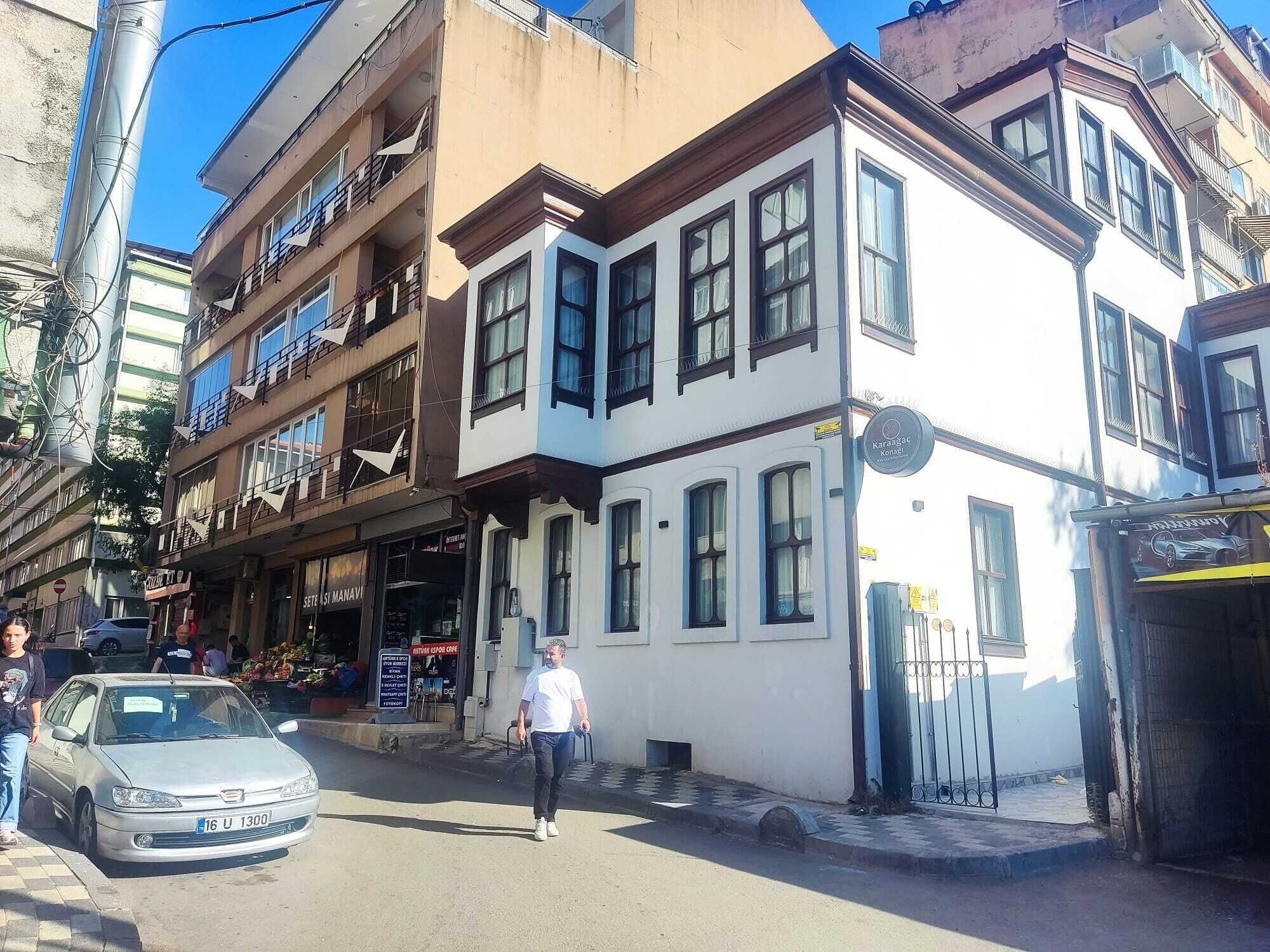 Une vue de rue avec un immeuble comprenant plusieurs étages, des balcons et un commerce situé au rez-de-chaussée.