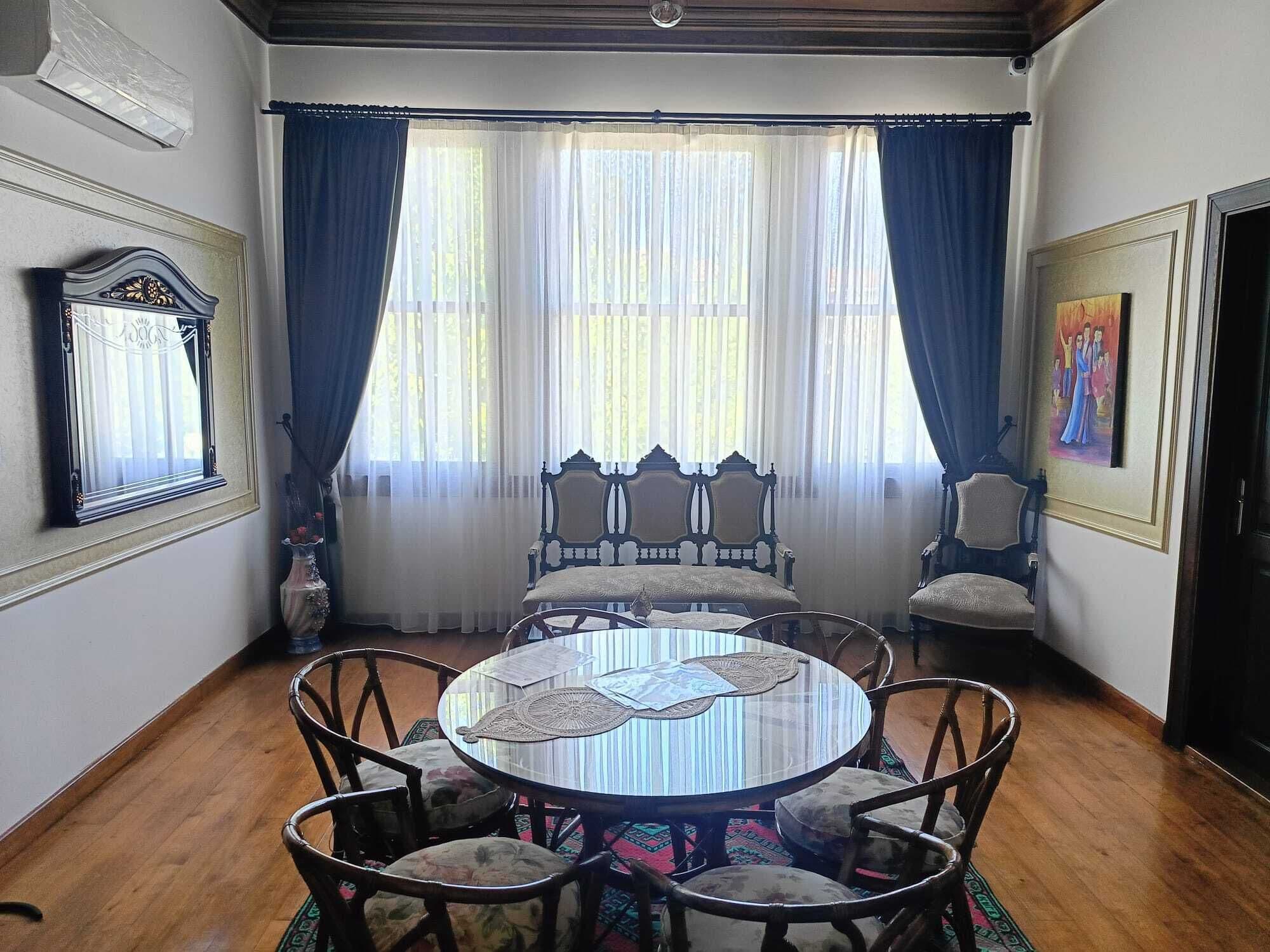 Un comedor con una mesa redonda, sillas y una ventana con cortinas.
