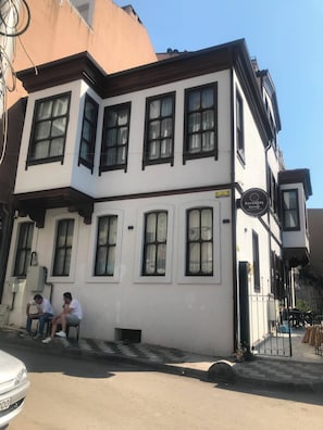 A two-story building with a white facade and black window frames. There is a sign on the right side of the building that reads 'Karaagac Konak.' - Karaagac Konagi Hotel (Bursa)