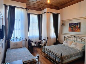 A room with two beds, a small table, and a chair. There is a painting on the wall. - Karaagac Konagi Hotel (Bursa)