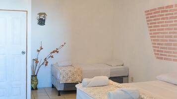 Un dormitorio con cama, candelabro, una puerta y pared de ladrillo.