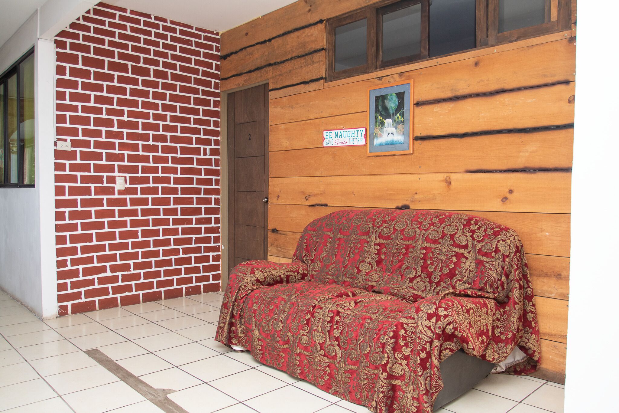 A room with a brick wall, wooden paneling, a couch, and a poster on the wall.