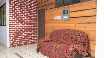 A room with a brick wall, wooden paneling, a couch, and a poster on the wall.