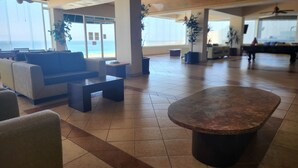 A spacious lobby with a seating area, a large coffee table, and a view of the ocean through large windows. - Calafia Resorts and Villas | Oceanfront Condo, Pools, Hot Tubs & Wellness Room 🌊 (Playas de Rosarito)