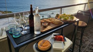 A table with a bottle, glasses, and food on a balcony overlooking the sea. - Calafia Resorts and Villas | Oceanfront Condo, Pools, Hot Tubs & Wellness Room 🌊 (Playas de Rosarito)