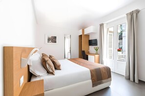Une chambre d’hôtel moderne équipée d’un lit, d’un bureau, d’une télévision et d’un balcon avec des rideaux.