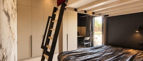 A bedroom with a bed, a ladder, a desk, and a chair.