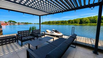 A covered outdoor seating area with a view of a lake and boats.