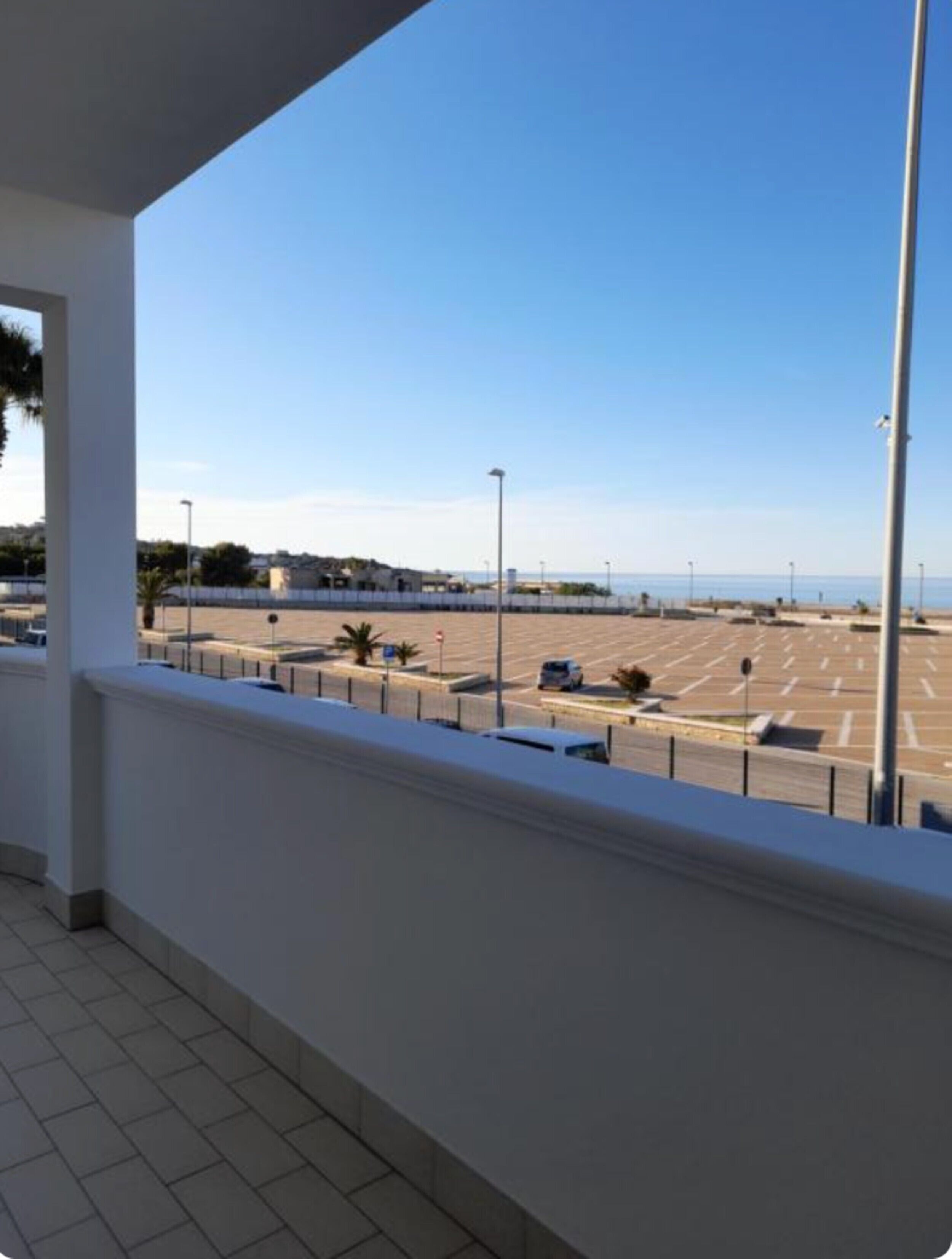 A balcony with a view of a parking lot and a distant body of water.