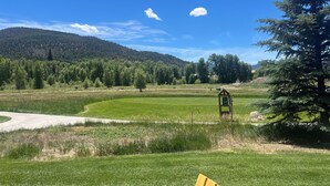 A grassy field with a wooden structure, trees, and a mountain in the background. - 3-bedroom townhome on Golf Course, Perfect Basecamp for Adventure or Relaxing (South Fork)