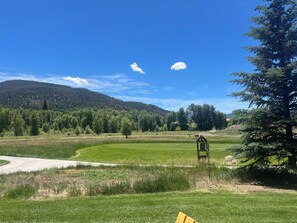 A grassy field with a wooden structure, trees, and a mountain in the background. - 3-bedroom townhome on Golf Course, Perfect Basecamp for Adventure or Relaxing (South Fork)