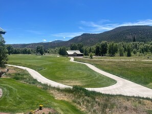 A golf course with a winding path, a building, and a forested mountain in the background. - 3-bedroom townhome on Golf Course, Perfect Basecamp for Adventure or Relaxing (South Fork)