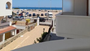 Blick auf einen Parkplatz, mit Autos und einem Strand im Hintergrund.