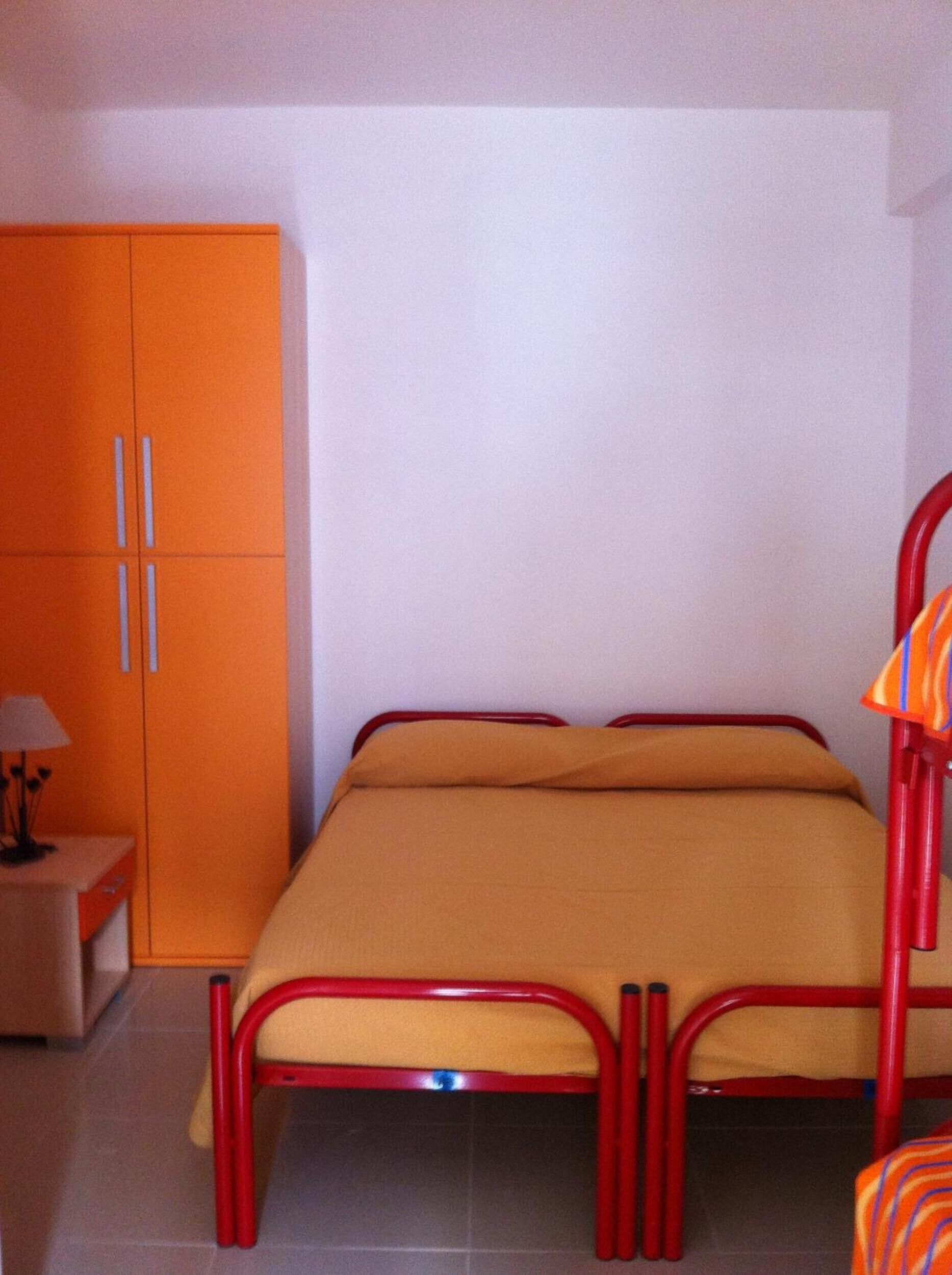 A room with a bed, a wardrobe, and a nightstand.