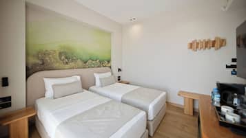 Une chambre d’hôtel avec deux lits, un tableau au mur, une tête de lit en bois et une petite table sur laquelle se trouve une bouteille d’eau.