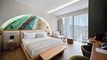A modern hotel room with a large bed, a seating area, and a view of the city.