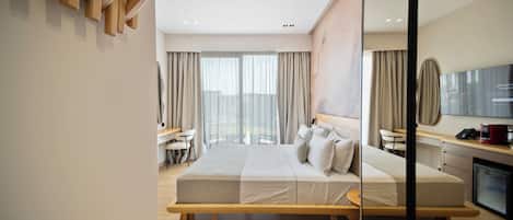 A modern hotel room with a large bed, a desk, and a view of the city.