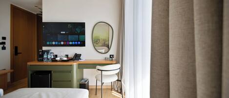 Une chambre d’hôtel avec un lit, un bureau doté d’un écran d’ordinateur, une chaise et une fenêtre avec des rideaux.