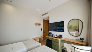 Habitación de hotel con dos camas, un escritorio con computadora, un espejo y una pequeña silla.