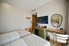 Habitación de hotel con dos camas, un escritorio con computadora, un espejo y una pequeña silla.
