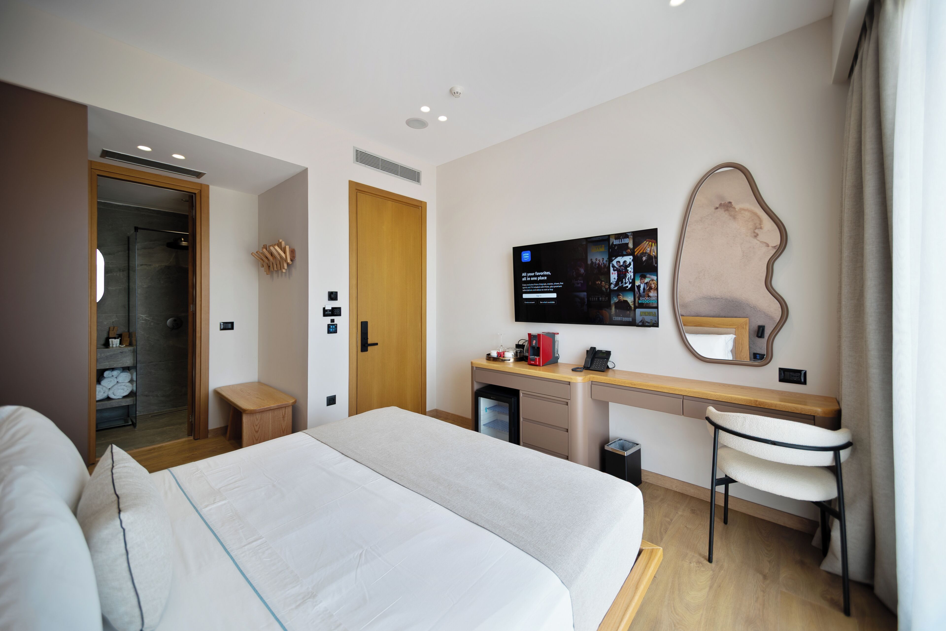 A hotel room with a bed, a desk, a chair, a television, and a mirror.