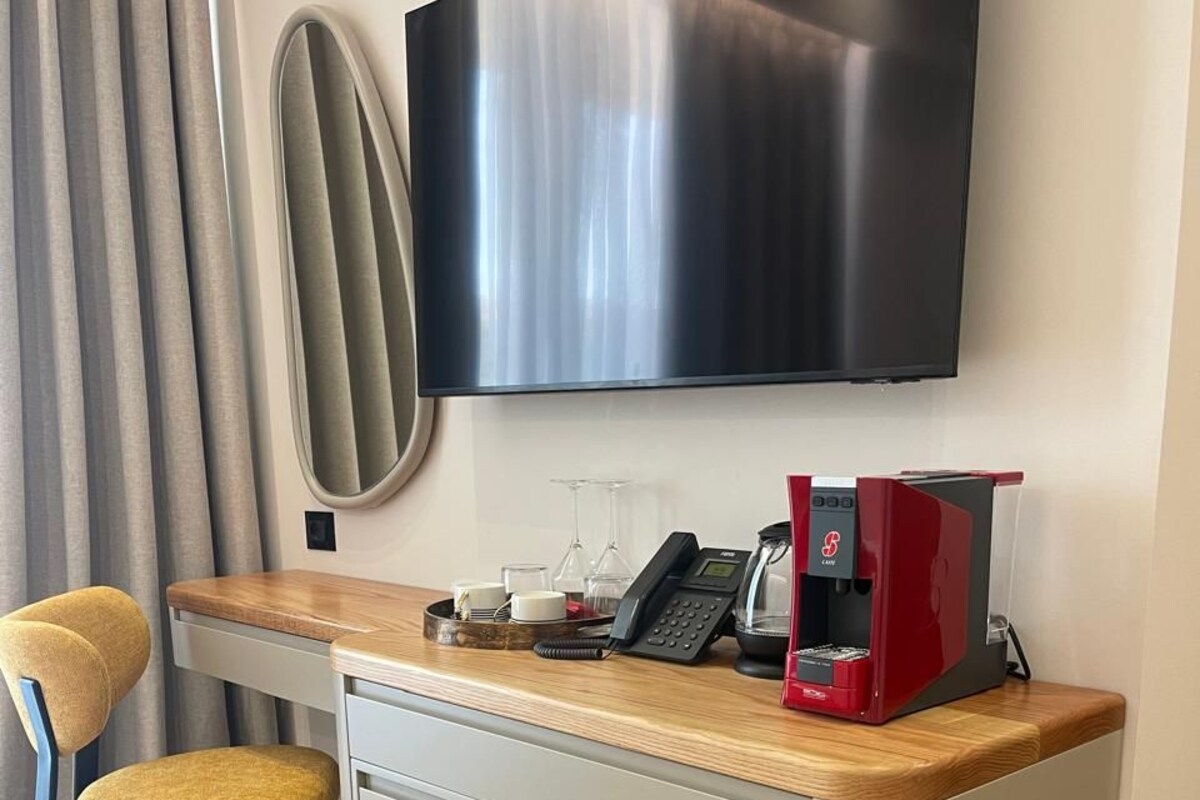 Cocina compacta con cafetera, teléfono y refrigerador pequeño.